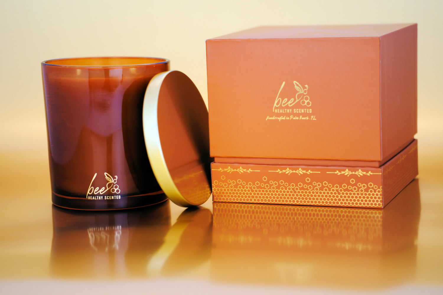 An amber gift box and an amber luxury candle jar depicting the Bee Healthy Scented Logo and Honeycombs at the bottom